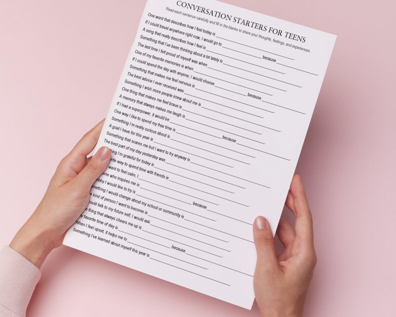 K&ouml;nnte beinhalten: Ein wei&szlig;es Blatt Papier mit dem Text "CONVERSATION STARTERS FOR TEENS" in Schwarz. Das Papier wird von H&auml;nden vor einem rosa Hintergrund gehalten. Der Text enth&auml;lt Aufforderungen zum Teilen von Gedanken, Gef&uuml;hlen und Erfahrungen.