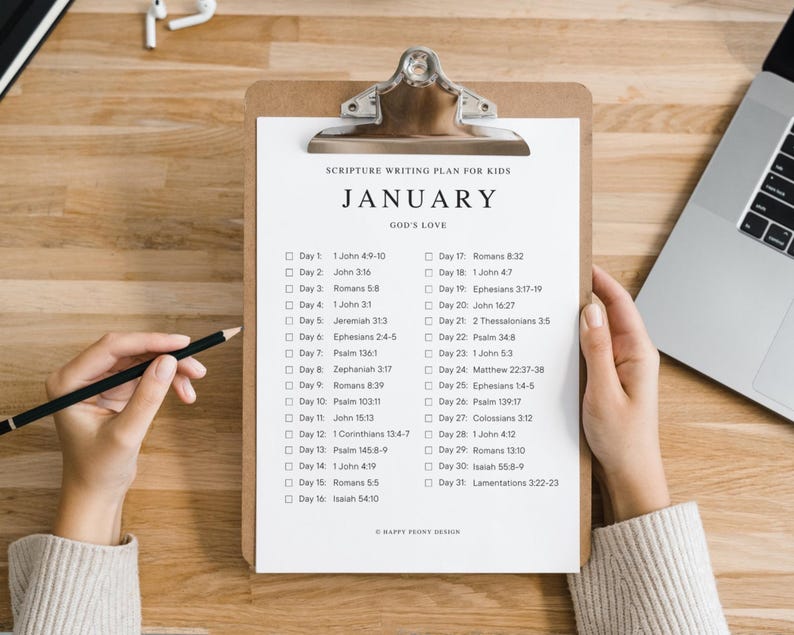 May include: A white clipboard with a black clip, titled "Scripture Writing Plan for Kids" with the month "January" and the words "God's Love" in black text. The clipboard has a list of Bible verses for each day of the month.