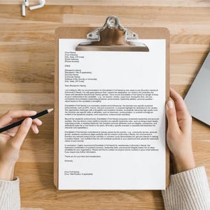 May include: A white letter of recommendation on a clipboard with a black clip. The letter is written in a formal tone and includes the words "Dear [Recipient's Name]" and "Sincerely".