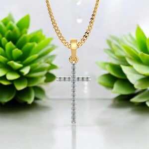 Puede incluir: Un collar de cadena de oro con un pequeño colgante de cruz engastado con diamantes.