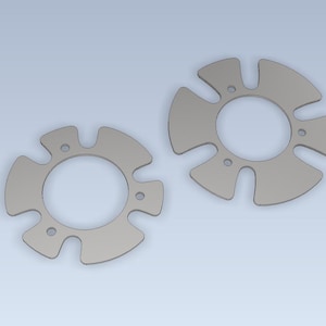 Pode incluir: Dois componentes metálicos circulares prateados com um design simétrico único. Cada peça apresenta um orifício central e quatro extensões curvas em forma de pétala, com pequenos orifícios circulares.