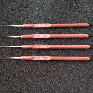 Puede incluir: Cuatro herramientas con mango rojo y puntas metálicas. Las herramientas están etiquetadas con 0,5 mm, 0,6 mm, 0,7 mm y 0,8 mm.