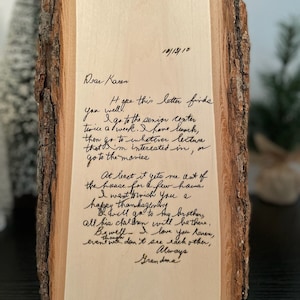 May include: A wooden plaque with a handwritten letter addressed to Karen, dated 10/13/10, from Grandma. The wood has a natural bark edge. The letter's text is in black ink on a light wood surface.