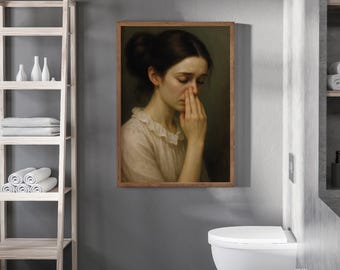 Peut inclure: Un portrait encadré d'une femme en robe claire, touchant son visage avec sa main. L'œuvre est accrochée à un mur gris au-dessus d'une toilette blanche. Une étagère en bois avec des serviettes et des bouteilles décoratives est à gauche.