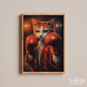Könnte beinhalten: Gerahmter Druck mit einer Katze mit roten Boxhandschuhen und einem roten Bademantel, bereit zum Kämpfen. Die Katze hat orange-weißes Fell und einen ernsten Gesichtsausdruck. Der Hintergrund ist dunkel.