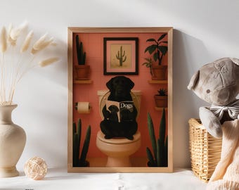 May include: A framed print featuring a black Labrador Retriever sitting on a toilet and reading a magazine titled "Dogs." The background includes a pink wall, potted plants, and a small framed cactus art piece. The print is in a wooden frame.