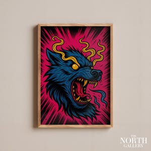 Könnte beinhalten: Ein gerahmter Kunstdruck mit einer stilisierten Illustration eines Wolfskopfes. Der Wolf hat blaues Fell, gelbe Augen und scharfe Zähne, vor einem leuchtend rosa und schwarzen Hintergrund. Das Kunstwerk hat einen kühnen, grafischen Stil.