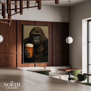 May include: A framed print featuring a gorilla holding a glass of beer. The artwork is displayed on a wooden wall in a modern interior setting. The North Gallery logo is visible at the bottom.