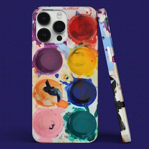 Puede incluir: Una funda blanca para iPhone con un diseño de paleta de pintura colorida. La funda presenta una variedad de colores, incluyendo rojo, amarillo, azul, verde y morado. La funda tiene un recorte para el objetivo de la cámara y un borde blanco alrededor del borde.