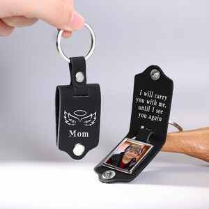 May include: Black leather keychain with a silver key ring. One keychain has the word "Mom" with angel wings and a halo. The other keychain has a photo and the text "I will carry you with me, until I see you again."