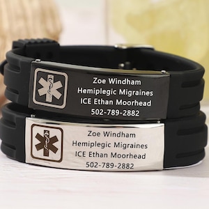 May include: Black silicone bracelet with two silver plates. The top plate has a medical symbol and the text "Zoe Windham Hemiplegic Migraines ICE Ethan Moorhead 502-789-2882". The bottom plate has the same medical symbol and the text "Zoe Windham Hemiplegic Migraines ICE Ethan Moorhead 502-789-2882".