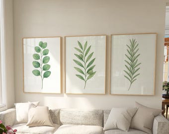 May include: Three framed botanical prints featuring watercolor illustrations of green leaves on a white background. The frames are a light wood color.