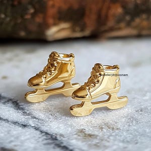 May include: A pair of gold-tone ice skate earrings. The earrings are detailed with a lace-up design and a blade.