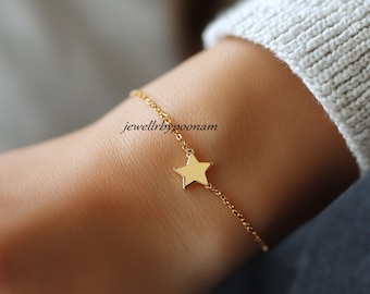 Puede incluir: Un delicado brazalete de cadena dorada con un pequeño dije de estrella. El brazalete está en la muñeca de una persona.