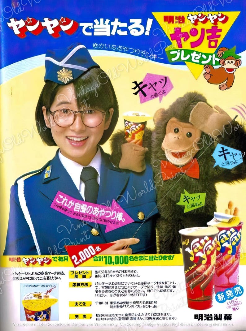 May include: A colorful Japanese advertisement for Yan Yan snack crackers. The ad features a woman in a blue uniform holding a monkey puppet. The text on the ad says "Yan Yan" and "New Release".