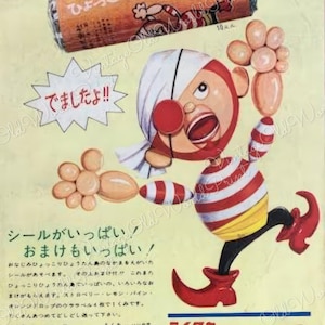 May include: A vintage Japanese candy advertisement featuring a cartoon character with a red and white striped shirt and a red nose. The character is holding a balloon and is standing on a yellow background. The text on the advertisement reads "ひょっこりひょうたん ドロップ" which translates to "Hyockori Hyotan Drop".