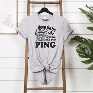 May include: Gray t-shirt with a black graphic that says "Keep Calm & Wait for the PING" and a drawing of a jar of pickles.