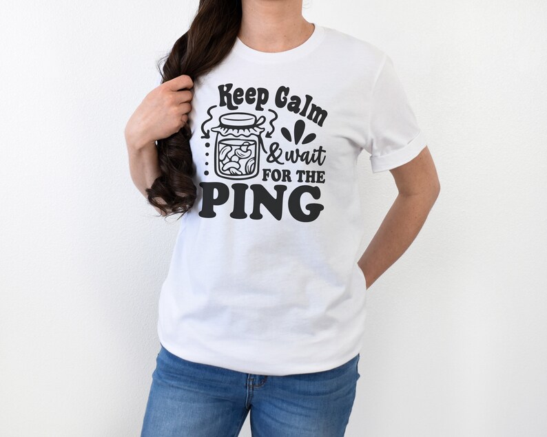 May include: White t-shirt with black text that reads "Keep Calm & Wait for the PING". The text is accompanied by a graphic of a jar filled with pasta.