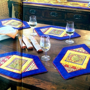 A rustic table setting with 5 table mats and in the background a side board with a table runner. There are 3 wine glasses and serviettes on the table.