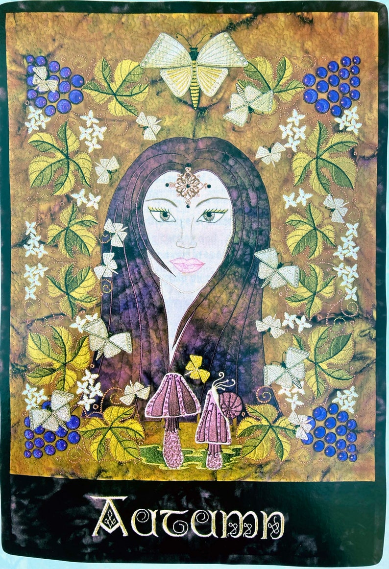 An embellished wallhanging featureing the image of a young woman with long brown hair surrounded by grapevines, white flowers and butterflys. At the base are two toadstools on which a snail sits. At the bottom of the hanging is the word Autumn.