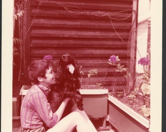 Coupe de cheveux de lutin femme heureuse câlins mignon chien épagneul noir dans un jardin de fleurs patio milieu du siècle photo instantané des années 1950, animaux de compagnie adorent 3