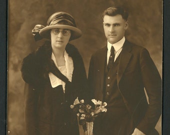 Elegant Young Couple Man Woman Vintage Studio Portrait Sepia Photo Beautiful Dress Hat Suit Vase of Flowers 1910s Fashion Vernacular