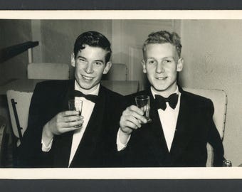 Vintage foto uit de jaren 60: Twee jonge mannen in smoking heffen het glas tijdens een galadate.