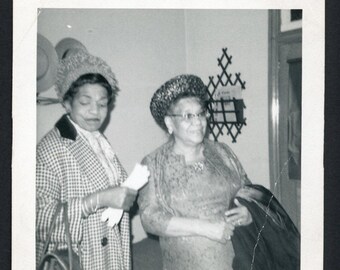 Vintage foto uit de jaren 60 van een oudere zwarte Afro-Amerikaanse vrouw in een hoed en handschoenen, gekleed in zondagse kleding.