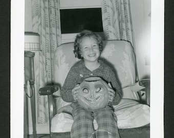 Vintage foto uit de jaren 1950: lachend meisje met griezelige Halloween pompoenhouder.