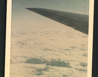 Vintage foto uit de jaren 60: vliegtuigvleugel, wolken, blauwe lucht, uitzicht door het vliegtuigraam. Abstracte afbeelding.