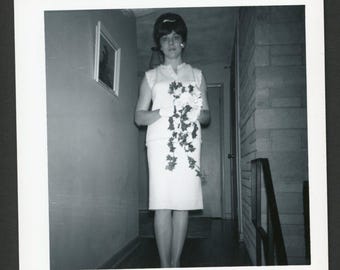Vintage foto uit de jaren 60: een prachtige bruid in een mouwloze schedejurk met een boeket bloemen.