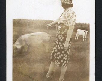Vintage foto uit de jaren 1930: vrouw met bloemenjurk en hoofddoek naast een varkentje of kalfje in boerderijstijl.