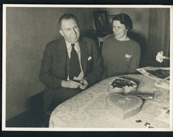 Paar mittleren Alters am Tisch mit herzförmigem Mann Schokolade Box Mann Frauen Spitze Tischdecke Vintage Foto Schnappschuss 1960er Jahre Mode Interior