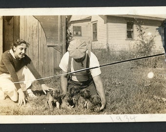 Frau und Pfeife rauchender Mann mit einem Arm voller entzückender Welpen mit Schlappohren, Vintage-Foto-Schnappschuss, Modehund, Haustiere, Familie aus den 1930er Jahren