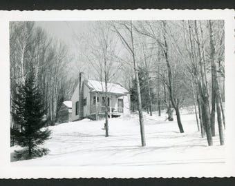 Vintage foto uit de jaren 1920: Gezellig huisje op een besneeuwde heuvel met winterse bomen en architectuur.