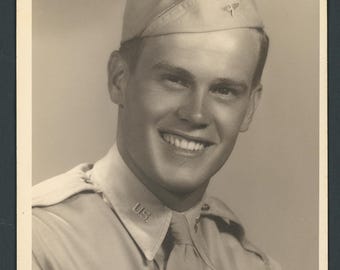 Retrato fotográfico vintage de estúdio, tamanho 5x7", década de 1940, de um belo e sorridente soldado do exército, em uniforme, gravata e chapéu, da época da Segunda Guerra Mundial.