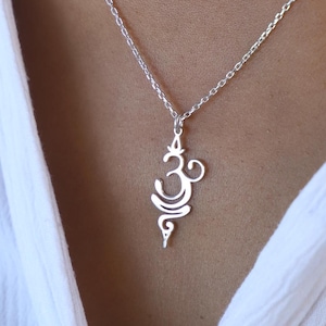 May include: A silver necklace with a delicate Om symbol pendant. The pendant is a stylized design of the Sanskrit word Om, a sacred sound in Hinduism.