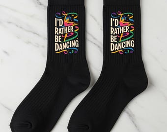 May include: Pair of black crew socks with the text "I'd Rather Be Dancing" in a colorful, stylized font. The socks have a ribbed texture and a classic design, suitable for casual wear.