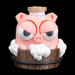 May include: A pink pig-shaped bath bomb dispenser with a grumpy expression. The pig is in a wooden tub with white foam and a light brown lid. The dispenser is designed to hold bath bombs.