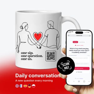 Peut inclure: Un mug en céramique blanc avec une illustration au trait noir représentant deux personnes se tenant la main avec un cœur rouge entre elles. Le texte indique one sip. one question. one us. et un QR code. Un smartphone affiche une interface web.