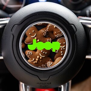 May include: A black steering wheel with a green "Jeep" logo and a close-up of gingerbread cookies in the center.