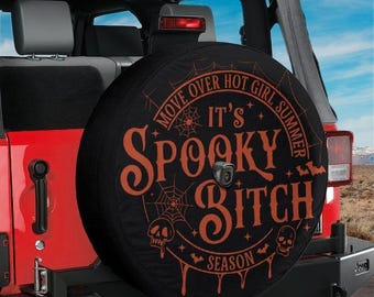 May include: A black circular spare tire cover mounted on the back of a red vehicle. The cover features orange text that reads Move Over Hot Girl Summer It's Spooky Bitch Season, surrounded by graphic illustrations of spiderwebs, bats, and skulls.