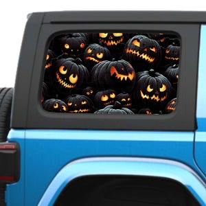 May include: A blue Jeep Wrangler with a rear window decal of a Halloween-themed design featuring a close-up of many jack-o'-lanterns with glowing orange eyes and mouths.