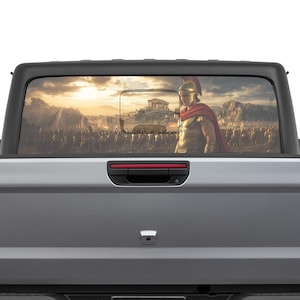 Puede incluir: Una sombrilla para la ventana trasera de un camión con una ilustración detallada de un guerrero espartano con armadura completa, con una capa roja, que domina un vasto ejército y un templo clásico. El fondo representa una puesta de sol sobre un paisaje montañoso.