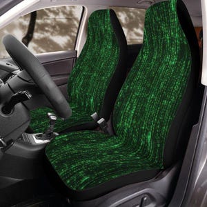 May include: Car seat covers featuring a green and black abstract design. The covers are fitted to the front seats of a car. The pattern has a vertical, textured appearance, with varying shades of green and black.