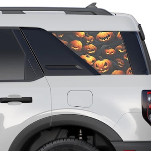 May include: A white SUV with a rear window decal featuring a pattern of orange pumpkins with spooky faces. The pumpkins are arranged in a random pattern and appear to be glowing.