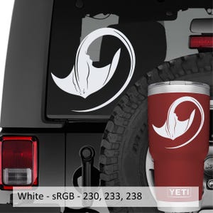 May include: A white vinyl decal featuring a stylized manta ray design applied to a dark vehicle window, alongside a matching red stainless steel tumbler with the same white manta ray graphic and the brand name YETI printed at the base.