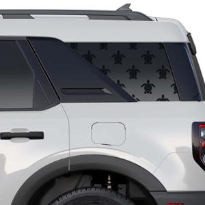 Könnte beinhalten: Ein weißes Sport Utility Vehicle mit einem Aufkleber am hinteren Seitenfenster, der ein sich wiederholendes Muster aus schwarzen Meeresschildkröten zeigt. Der Aufkleber bedeckt die Glasfläche mit mehreren Schildkrötensilhouetten.