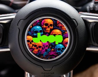 May include: A circular steering wheel emblem featuring a vibrant, multicolored pattern of skulls in shades of orange, blue, purple, and pink. Centered over the skull design is the word Jeep printed in a bright, solid lime green font.