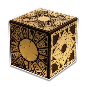 May include: A black cube puzzle box featuring intricate gold-colored metallic overlays on each face. The design includes geometric patterns, circular center elements, and detailed engravings across the surface of this decorative object.